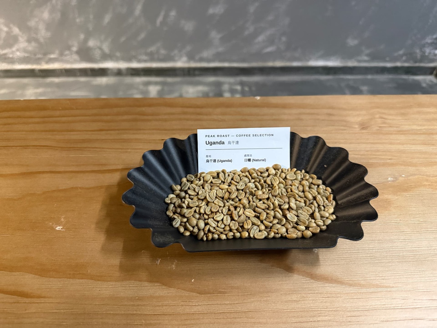 Uganda Natural — green coffee on a black fluted tray