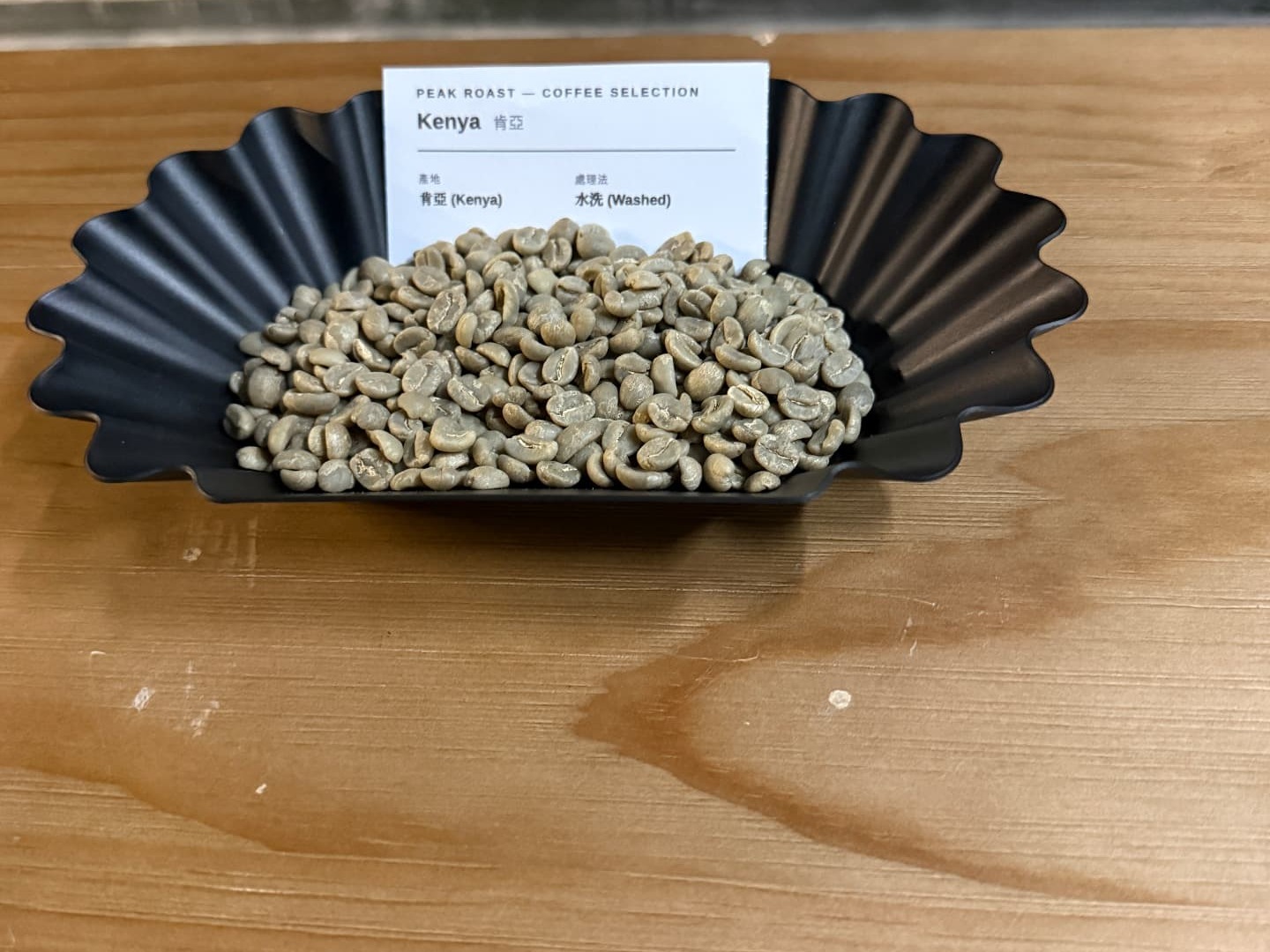 Kenya Washed — green coffee on a black fluted tray